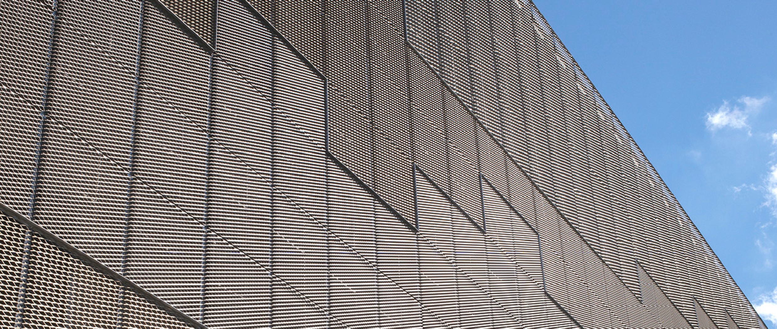 Det store stationsanlæg i Tjele, løftes op af en mørk betonbase, hvorefter den er blevet beklædt med strækmetal i forskellige anodiseringer og størrelser.