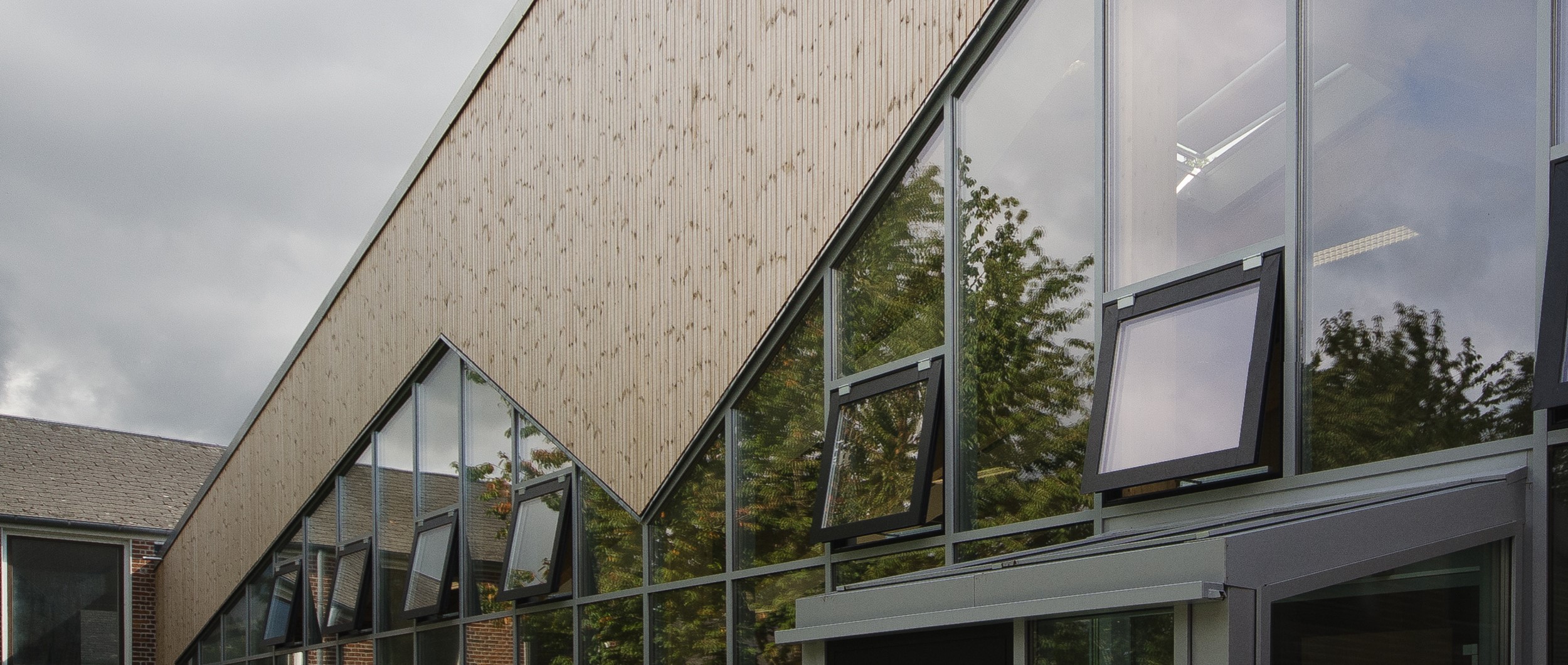 Facaden af den nye bygning er udført af varmebehandlet træ, som over tid patinerer i mange fine grå nuancer, og kræver minimalt vedligehold.